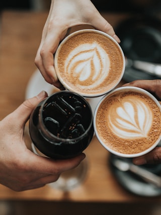 three person holding beverage cups