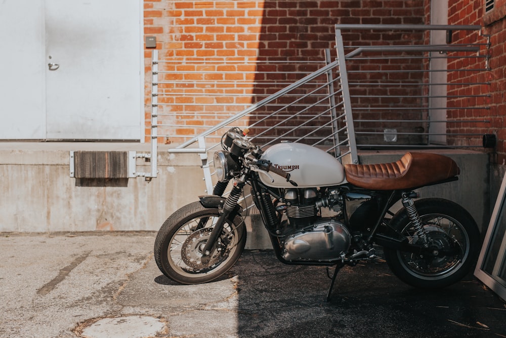 motocicleta cruiser branca e marrom ao lado de grades de aço cinza