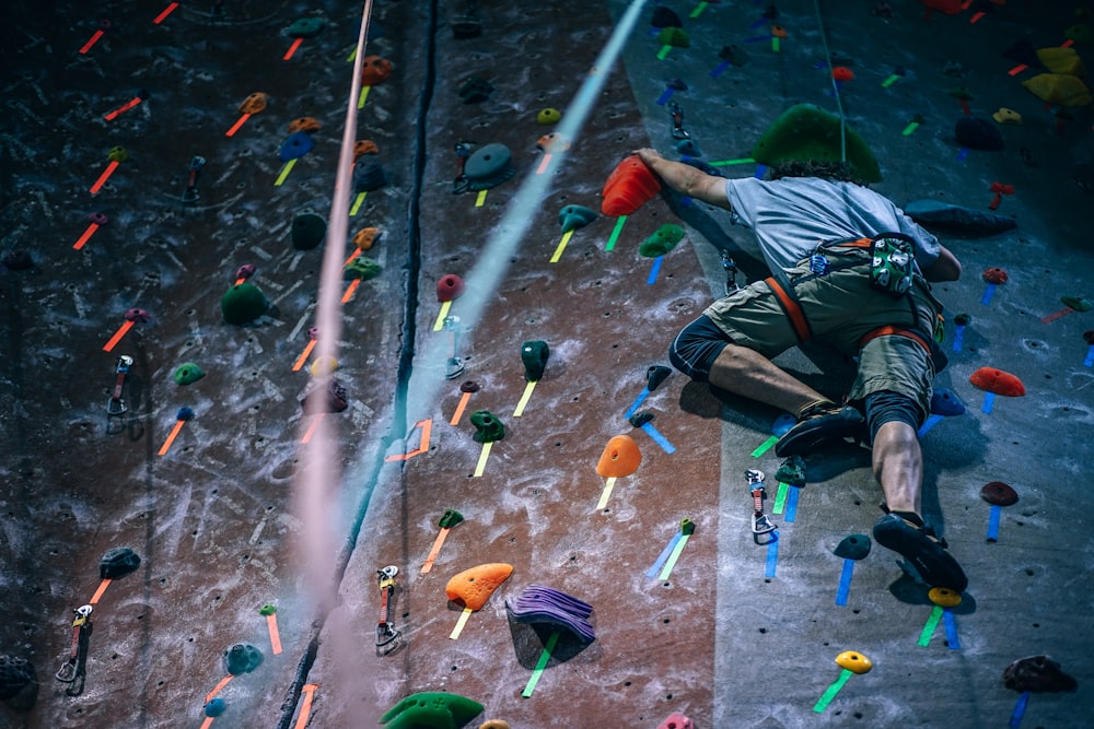 Athletes climb rock wall and use ropes and grip rocks