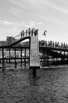 Black and white dynamic group photo of verticalvoid team bungee jumping with Pyrenean mountains and cliffs in the background, showing excitement and teamwork.