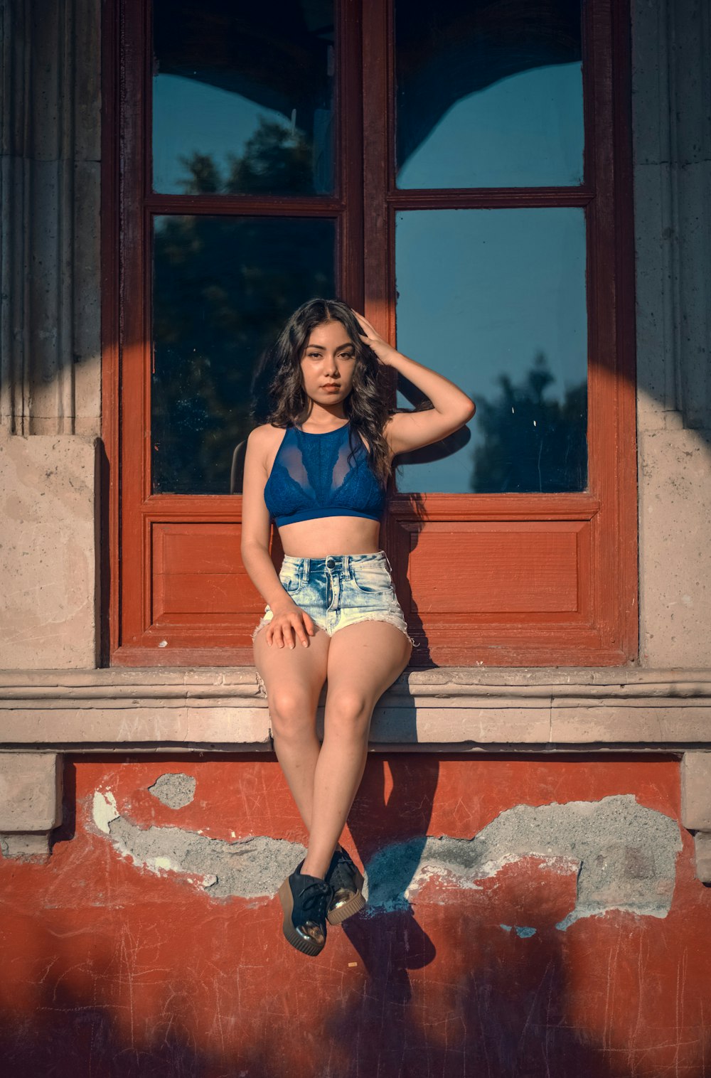 woman sitting on window holding hair