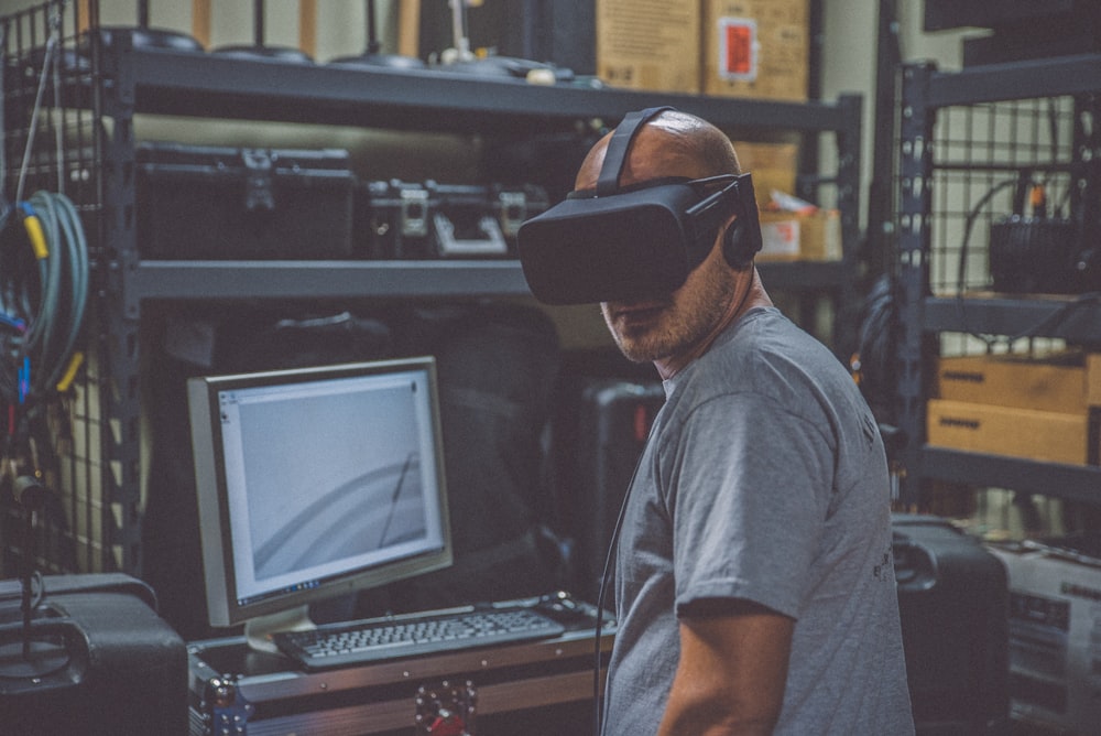 person using black VR Headset in front of computer