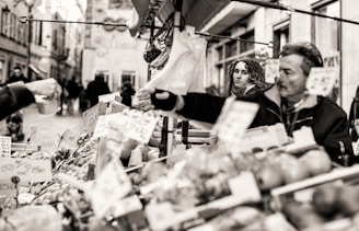 A candid black and white photo of a street vendor interacting with customers.