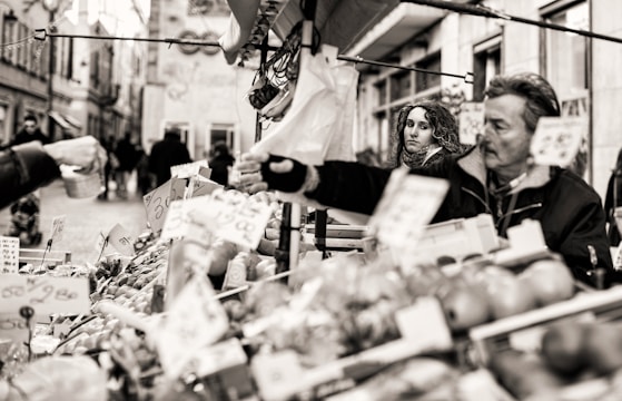 A candid black and white photo of a street vendor interacting with customers.