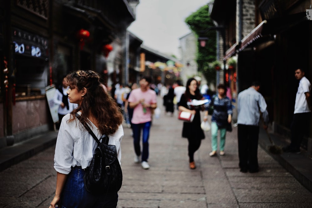 Woman walks through a diverse crowd on a busy city street