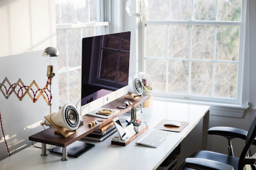 A tidy modern office desk with cleaning supplies and a sparkling computer screen.