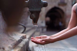Close-up of hands fixing a leaking faucet with a wrench in a cozy kitchen