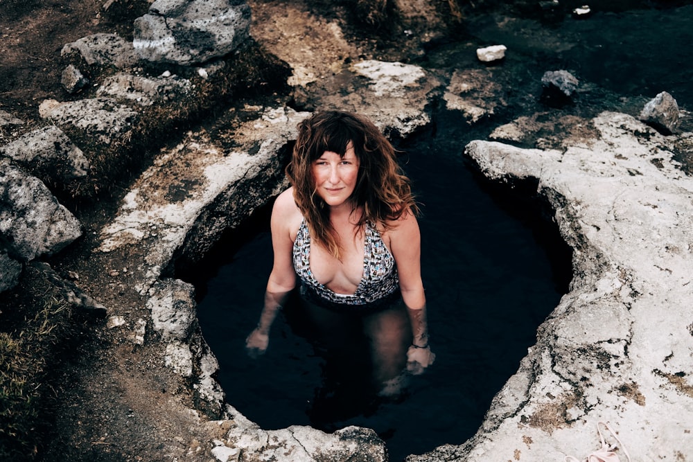 woman in cave wearing one-piece swimsuit looking upward