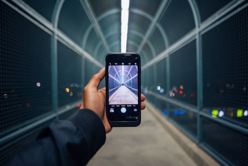 personne tenant un téléphone montrant un tunnel vide