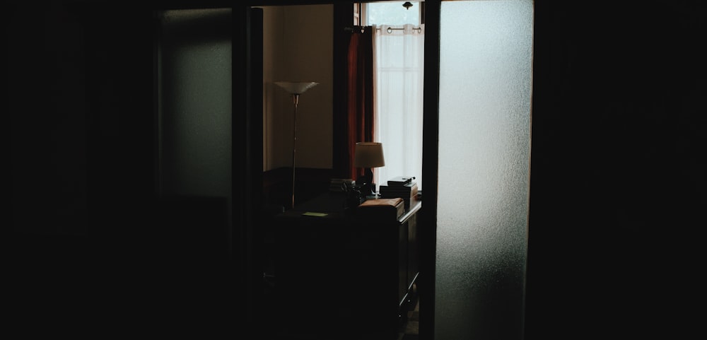 Pasillo oscuro que conduce a la oficina con escritorio y lámpara