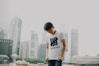 man looking at his shirt with buildings background
