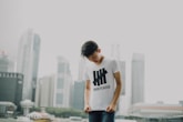 man looking at his shirt with buildings background