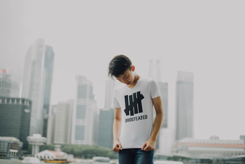 man looking at his shirt with buildings background