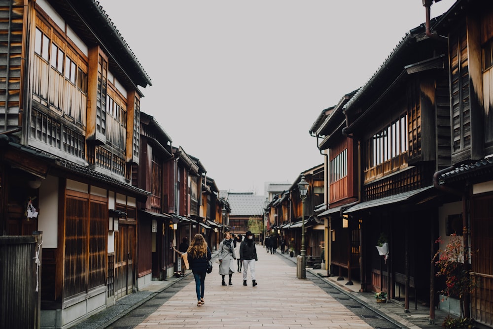 people walking on the street between brown wooden buildings during daytime