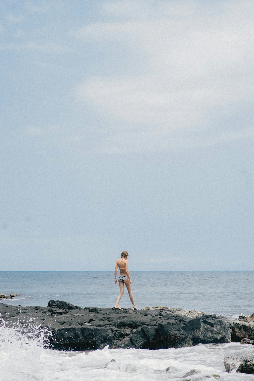 woman standing on rock surrounded by the body of water