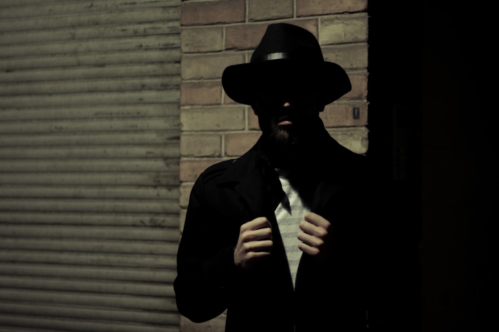 hombre vestido con sombrero de fieltro negro y chaqueta de traje negro