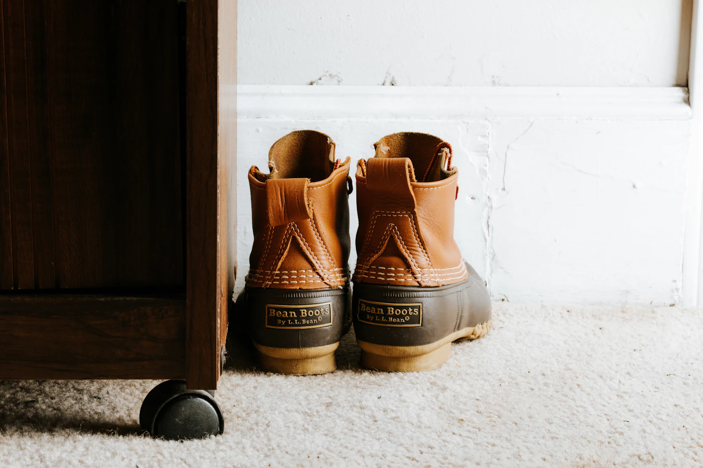 Botas de cuero café con suela de hule junto a un mueble de madera