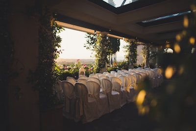 Guests seated on wooden chairs facing the sea, decorated with white ribbons.