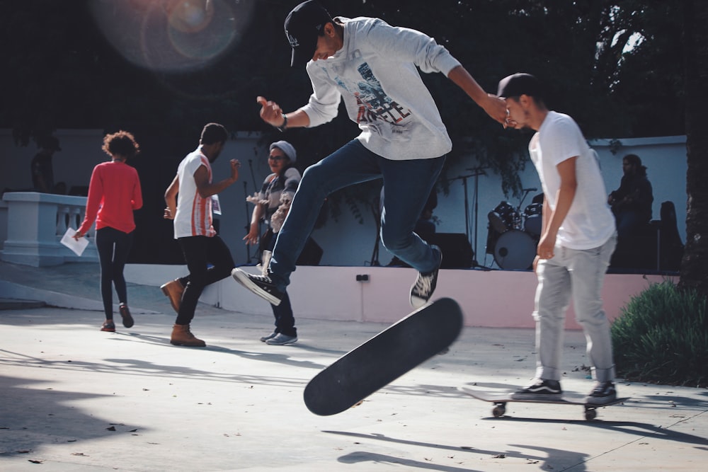 man in white t-shirt and black pants holding skateboard