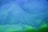 A close-up view of a translucent mesh fabric with a flowing, wavy texture in shades of blue and green. The overlapping layers create a complex, artistic pattern, evoking a sense of mystery and fluidity.