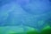 A close-up view of a translucent mesh fabric with a flowing, wavy texture in shades of blue and green. The overlapping layers create a complex, artistic pattern, evoking a sense of mystery and fluidity.
