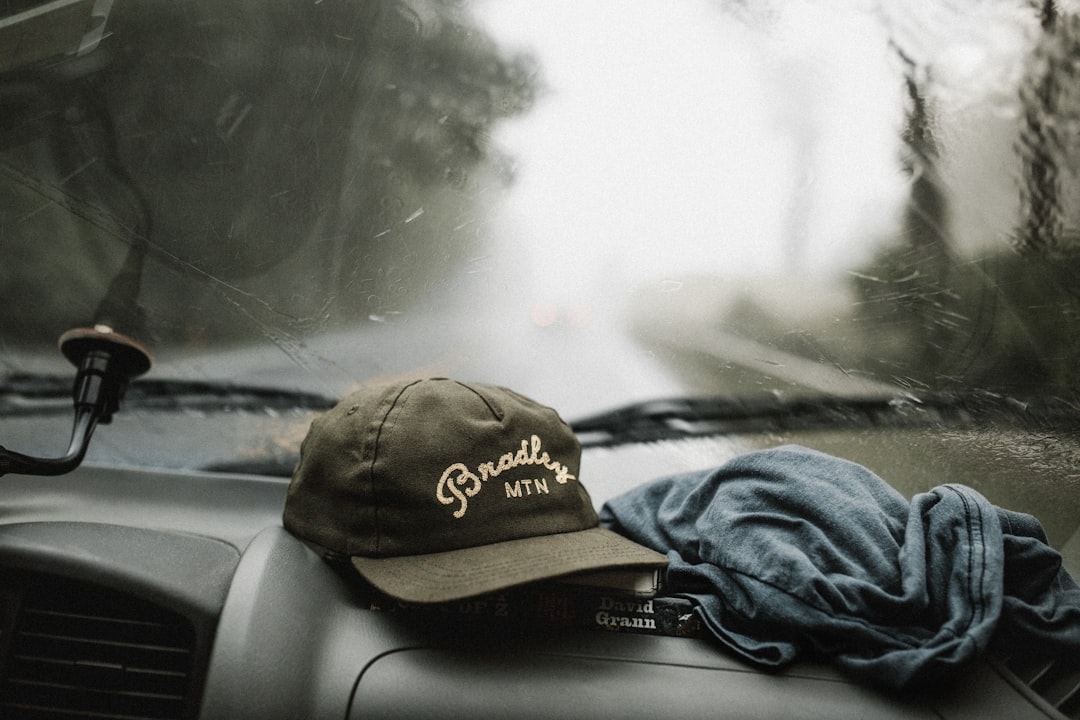 black and white baseball cap near grey shirt on top of glove compartment inside car, Instagram - @andrewtneel | Donation