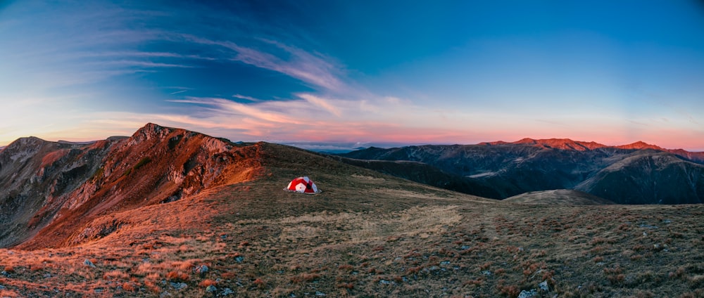 낮에는 산 꼭대기에 빨간색과 흰색 캠핑 텐트