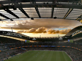 A vibrant soccer ball soaring into a stadium filled with cheering fans at sunset.