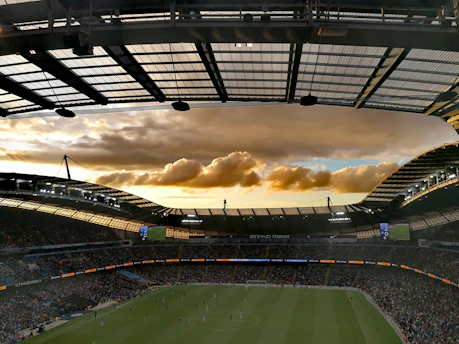 A vibrant soccer ball soaring into a stadium filled with cheering fans at sunset.