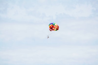 person on parachute sky diving under cumulus clouds red sox zoom background