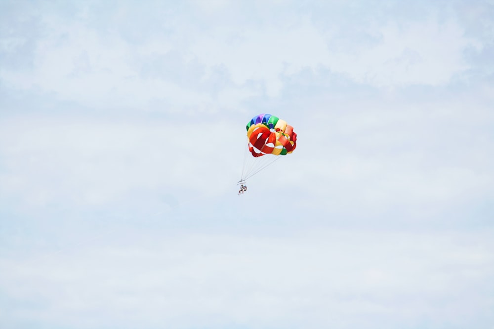 person on parachute sky diving under cumulus clouds
