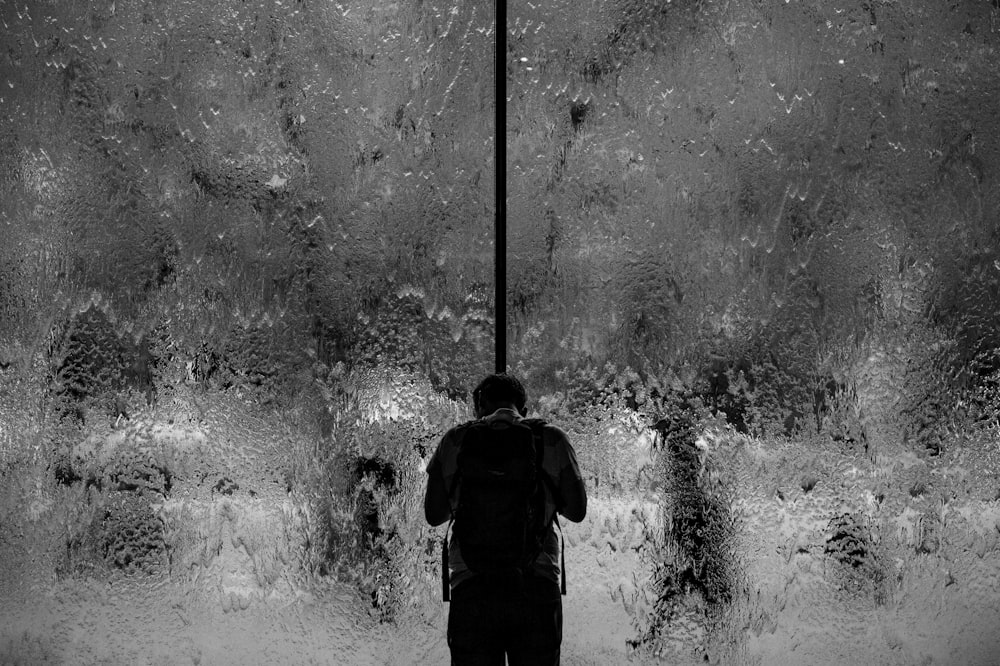 uomo in piedi sulla parete di vetro con acqua versante