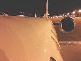 A jet engine close-up with reflections of the runway lights during dusk.