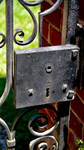 A sturdy traditional house lock mounted on a rustic twin paddock gate under soft sunlight.