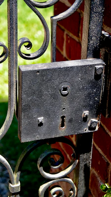 A sturdy traditional house lock mounted on a rustic twin paddock gate under soft sunlight.