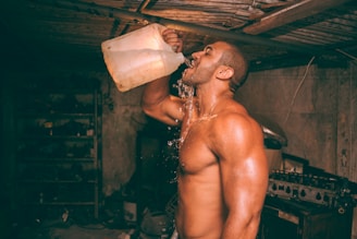 topless man drinking water from plastic container