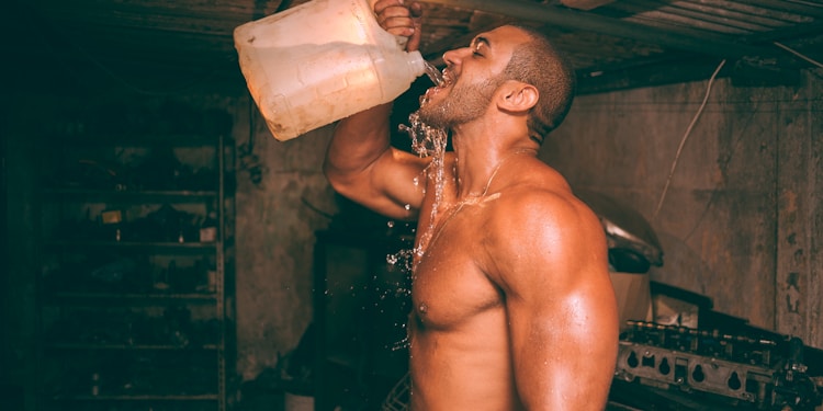 topless man drinking water from plastic container
