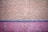 The image features a textured wall with abstract patterns. The upper portion of the wall is painted in a beige color, while the lower portion is pink, separated by a thin blue line. The surface has rough, uneven protrusions giving it a rustic, unfinished look.
