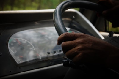 Close-up of a hands on a steering wheel while driving on a highway during daylight.