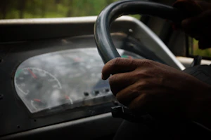 A close-up of a learner’s hands on the steering wheel with a dashboard view.