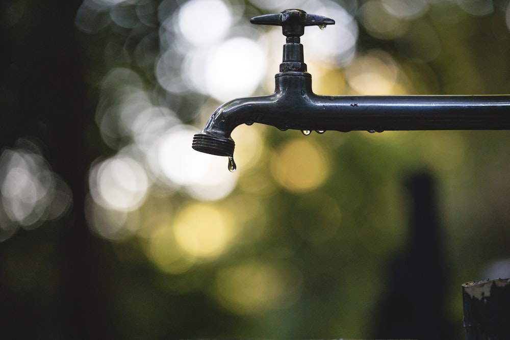 tilt shift lens photography of black steel faucet