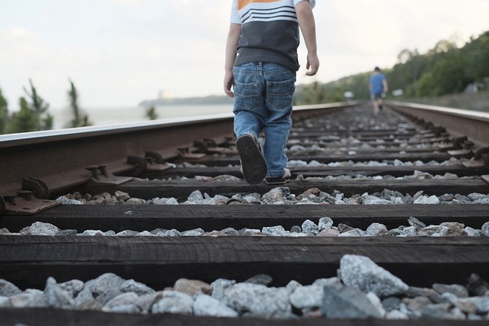 criança andando no trilho do trem durante o dia