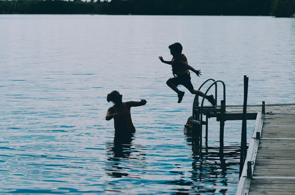 photography of boy jumping on body of water during daytime