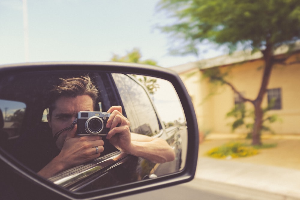 hombre tomando foto del espejo del coche