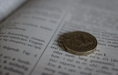 A vintage French coin resting on an open book about numismatics.