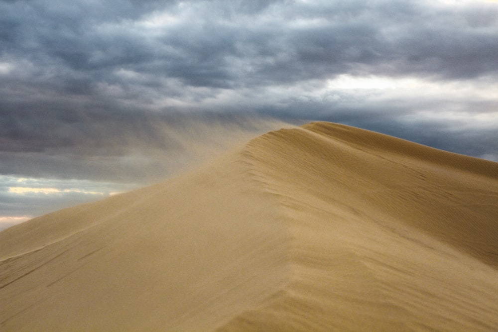 brown sand under white clouds during daytime