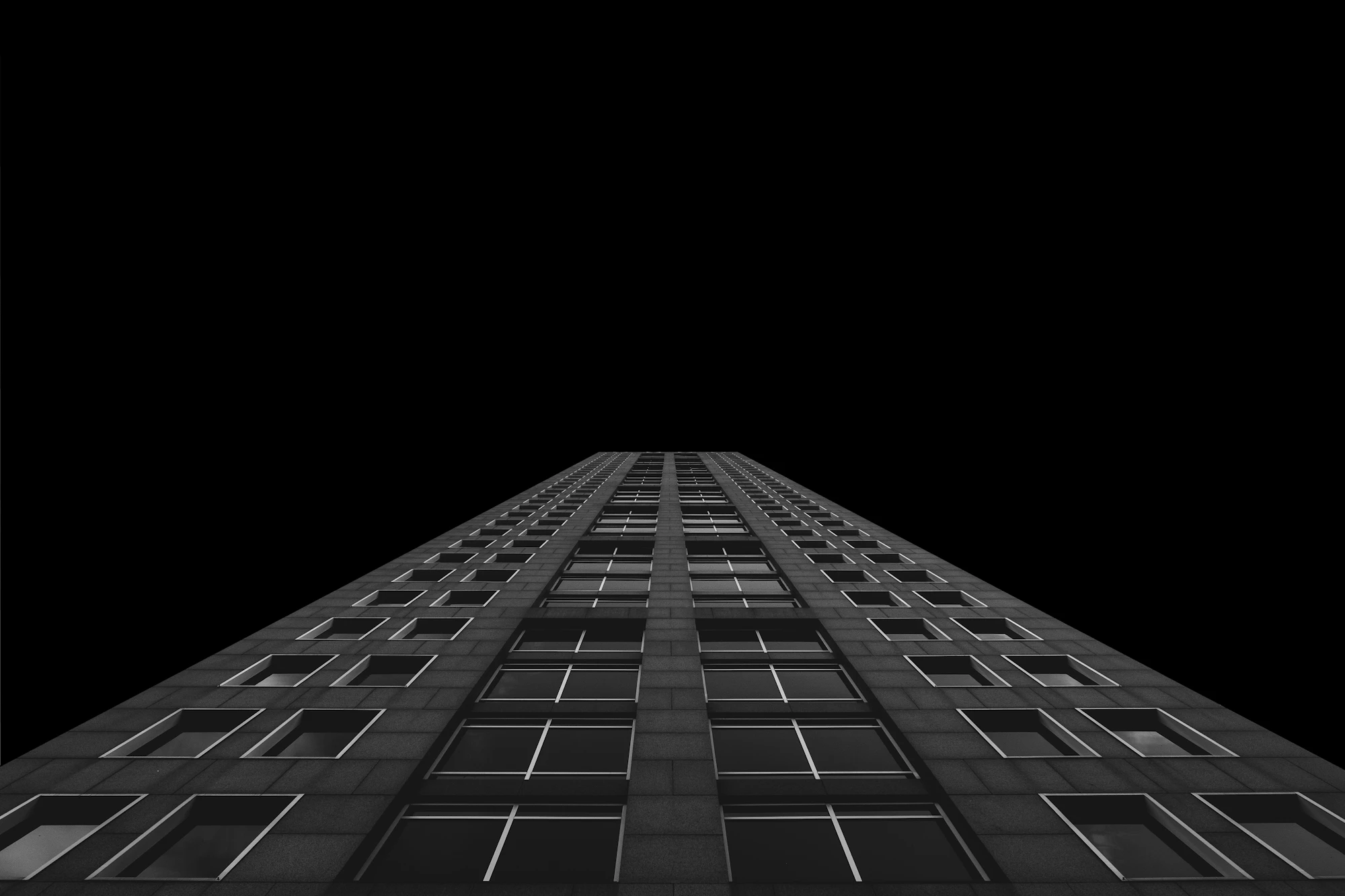 Looking straight up a tall office tower into a black night sky