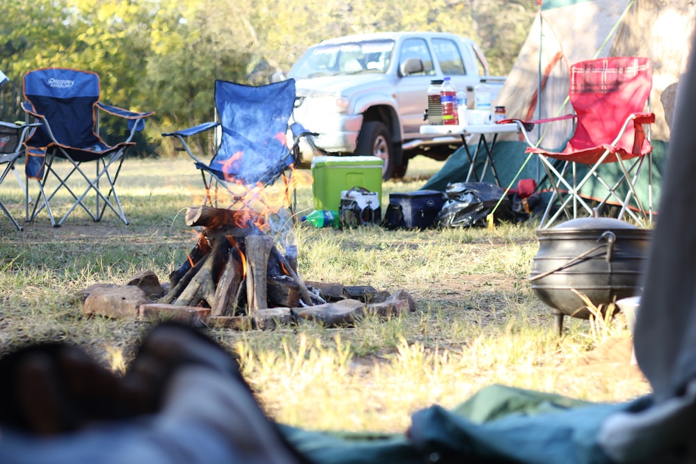 Campingstühle vor Lagerfeuer in der Nähe von Pickup