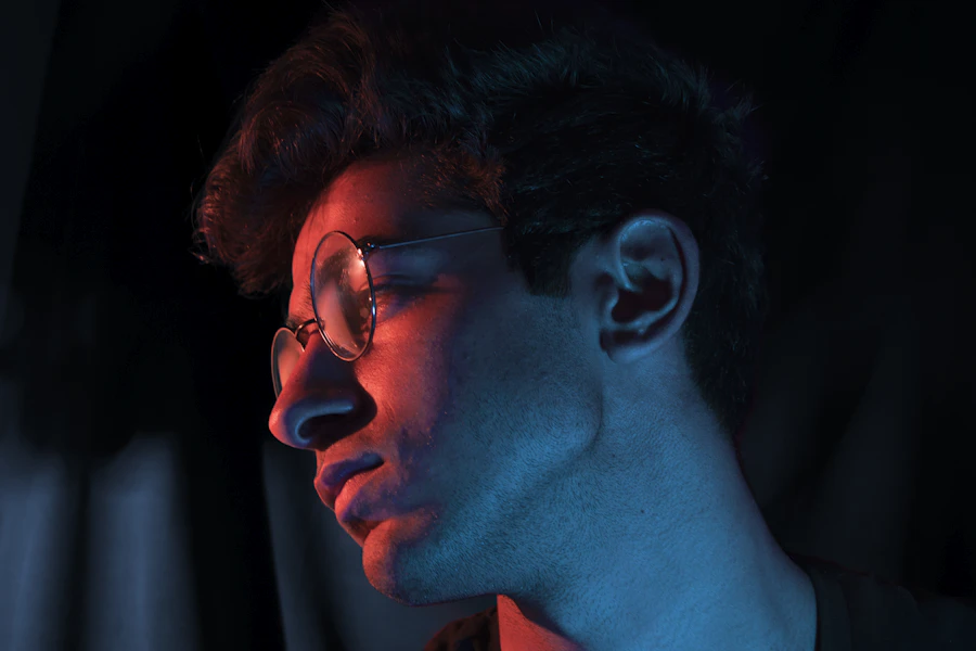 Young man wearing glasses in a dark room lit by neon