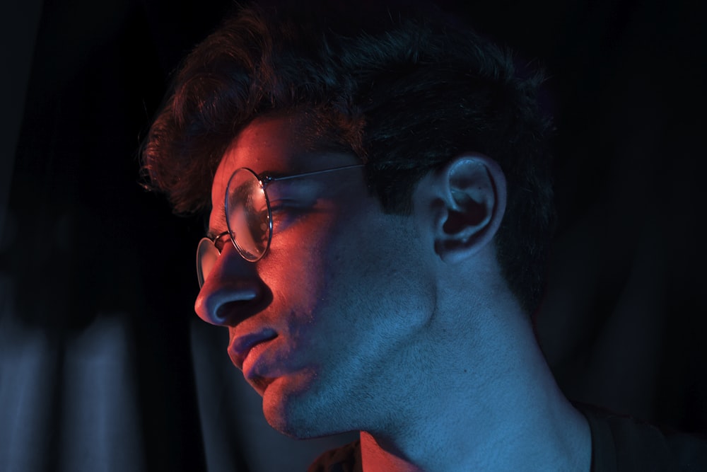 a young man wearing glasses in the dark
